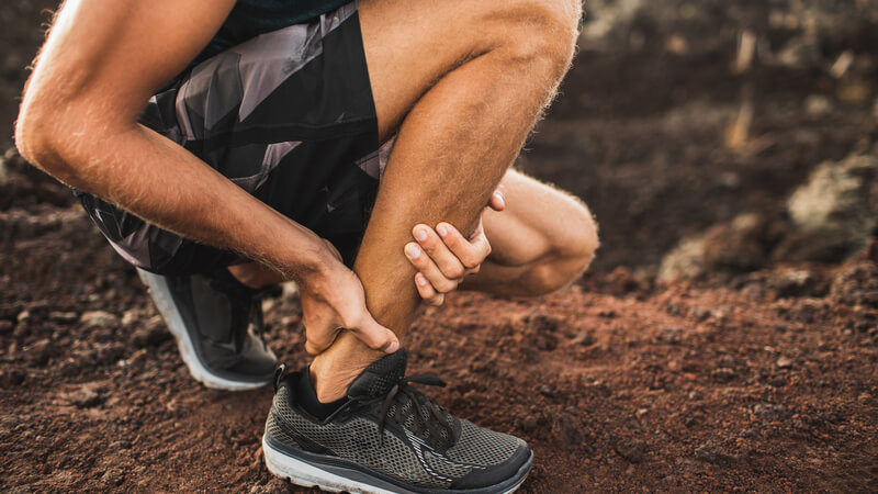 Runner bending down and holding ankle