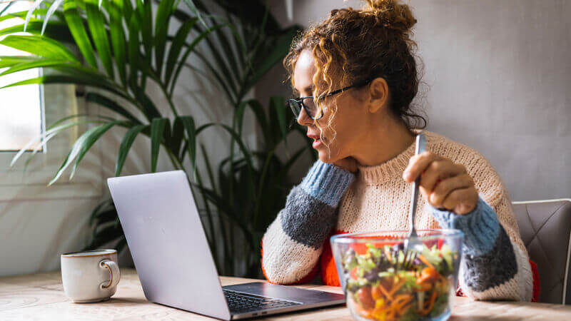 Woman eating and working on computer at the same time.